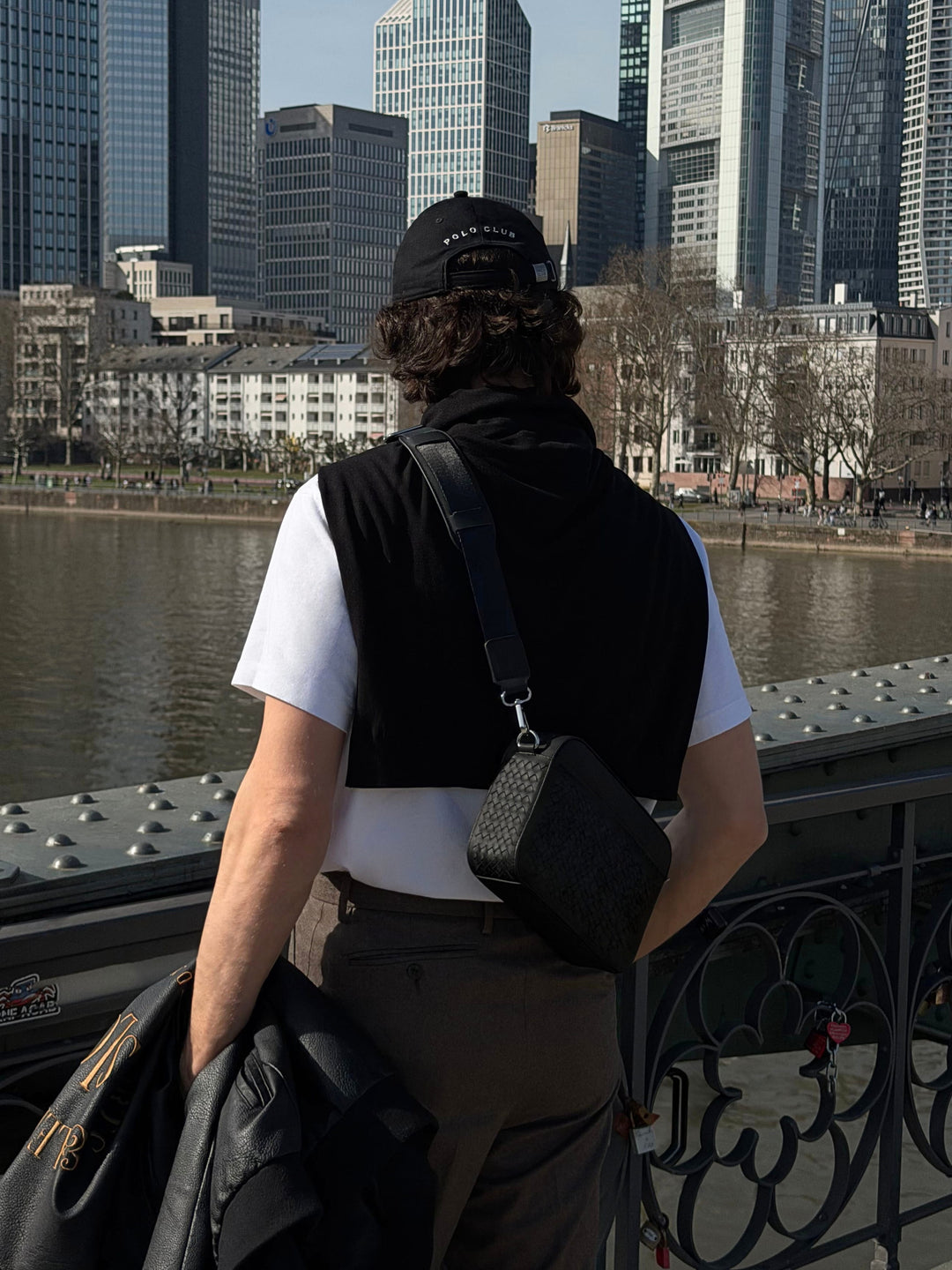 Geflochtene Umhängetasche Juno in Schwarz als Crossbody Bag für Herren, getragen aus der Rückansicht in urbaner Umgebung