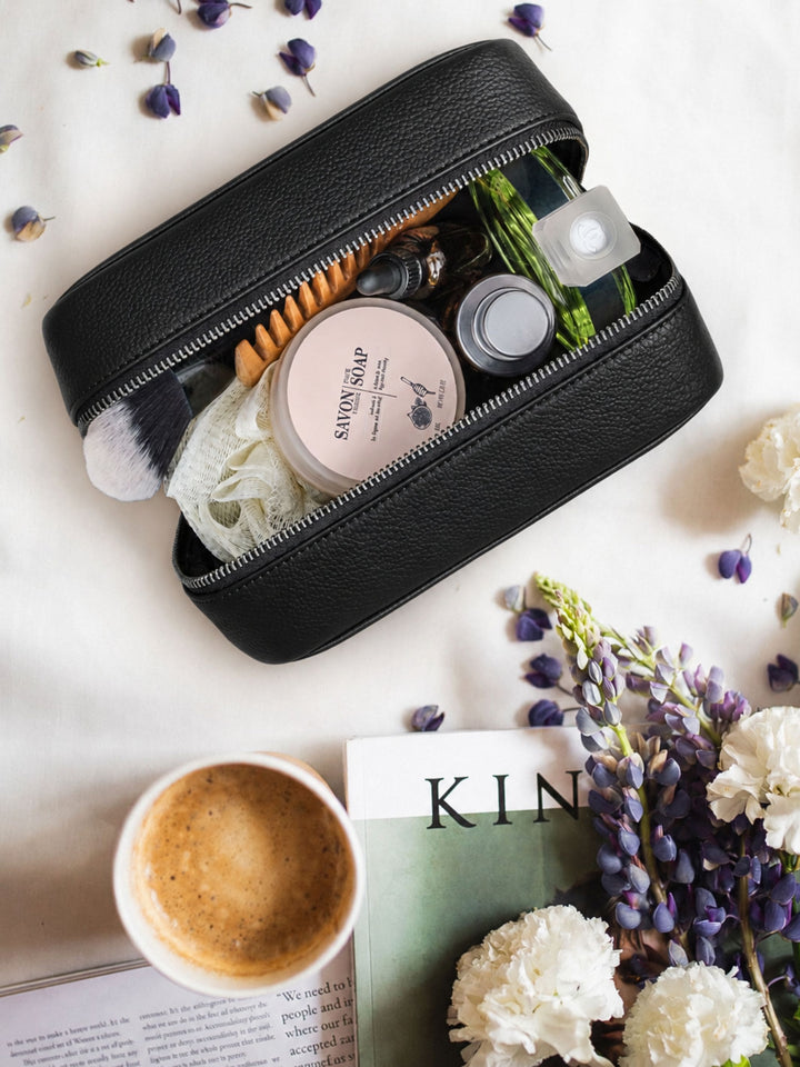 MIRA Kosmetiktasche aus schwarzem Leder im Lifestyle-Setting mit Pflegeprodukten